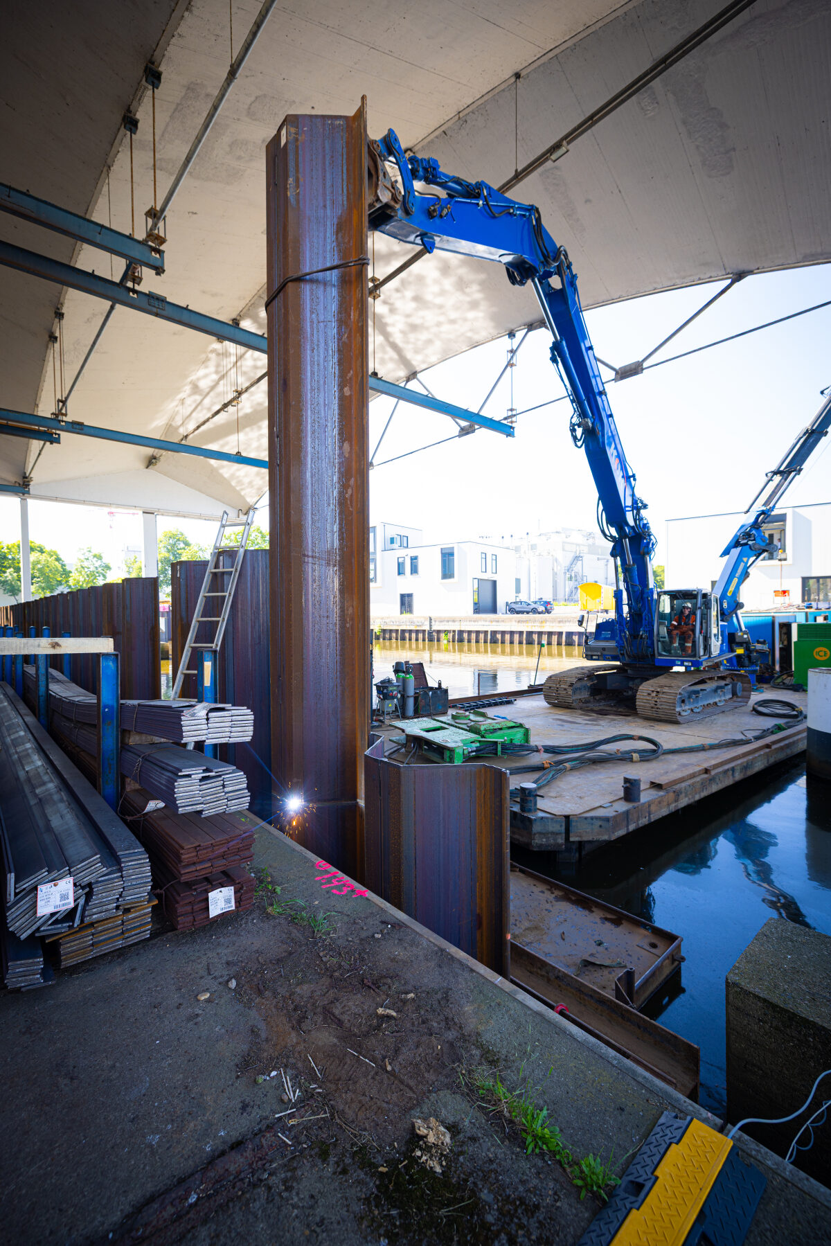 Het intrillen van damwanden onder de overkapping van een bedrijfspand bij het project Stadsdijken Zwolle