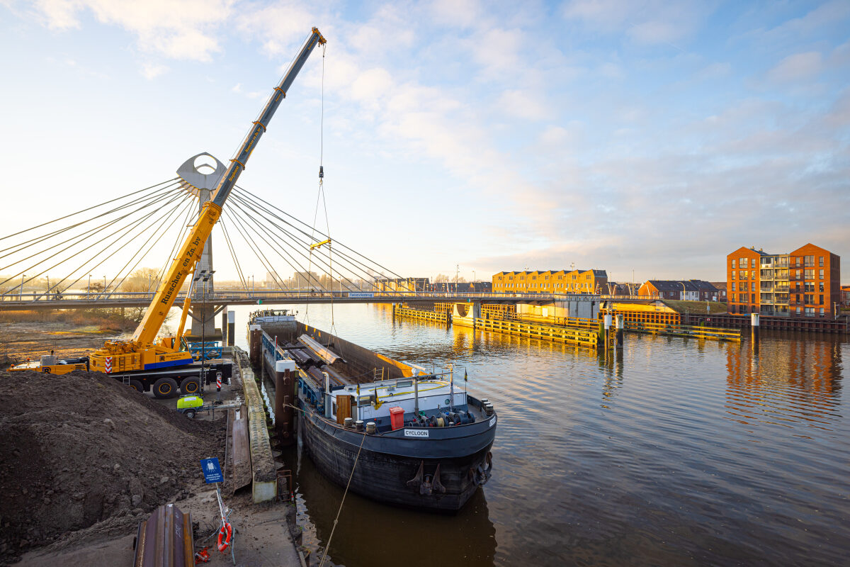 Damwanden worden aangevoerd per schip met op de achtergrond de Twistvliegbrug in Zwolle