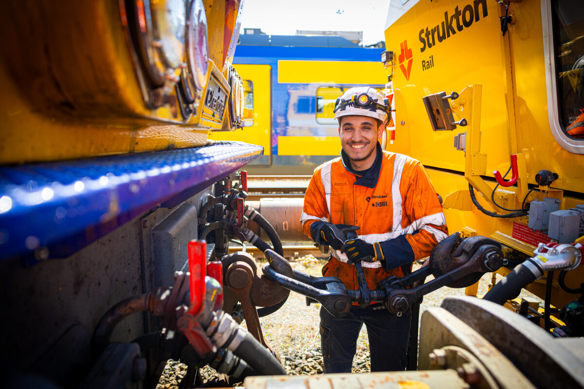 Een machinist is bezig met de koppeling tussen een locomotief en een werktrein