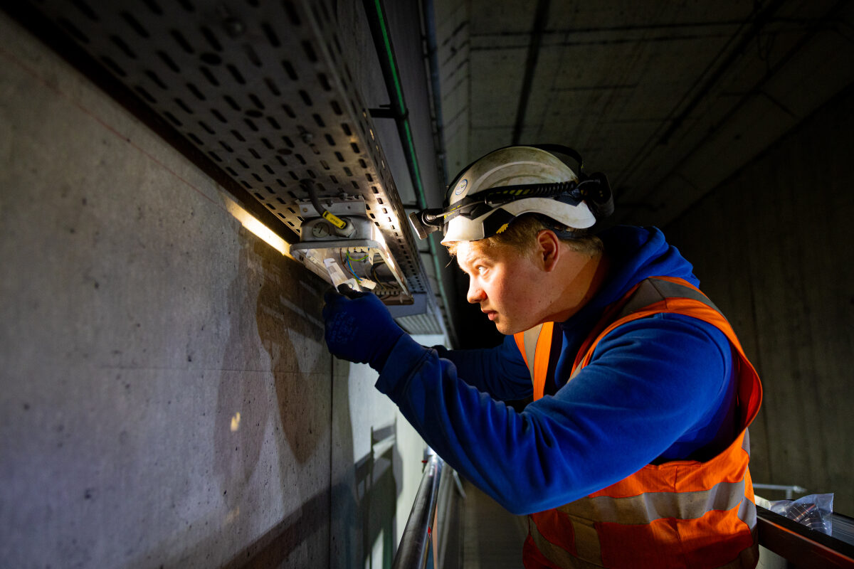 Een technisch medewerker vervangt oude TL-verlichting voor nieuwe duurzame LED-verlichting in een spoortunnel