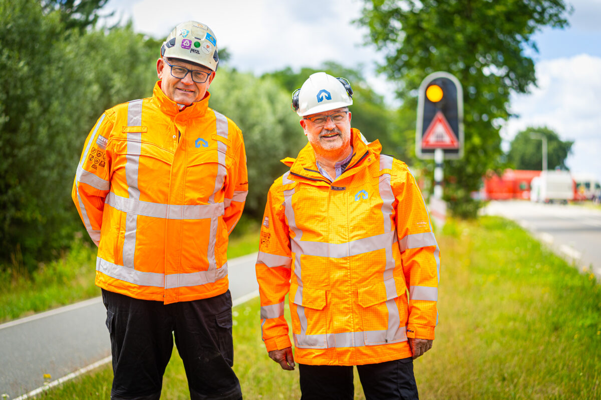 Twee medewerkers van een spooraannemer bij een technische installatie bij een spoorwegovergang bij Klarenbeek