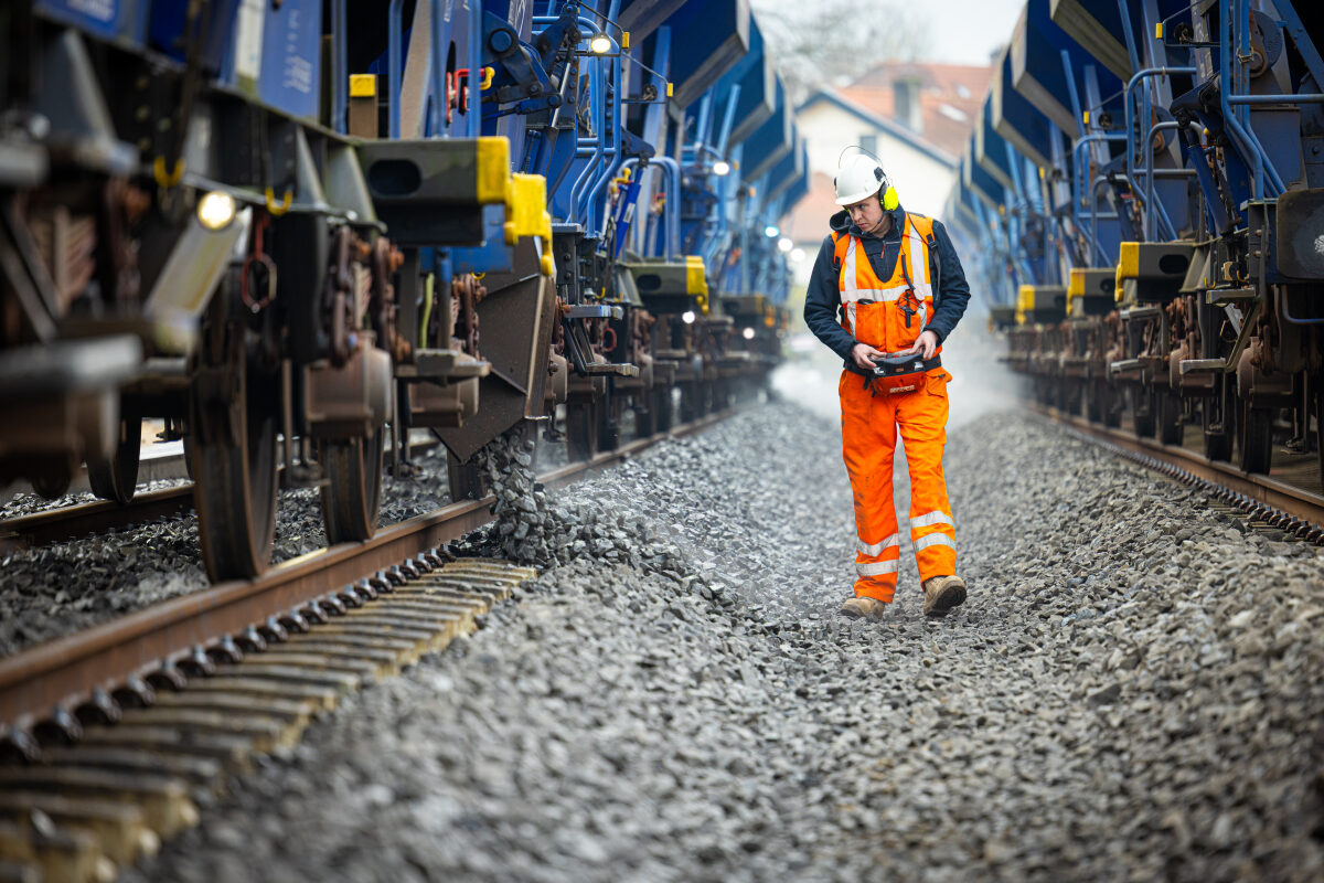 Het storten van ballast met speciale wagons die de ballast nathouden tegen de verspreiding van kwartsstof bij de bouw van het nieuwe emplacement bij station Nijmegen