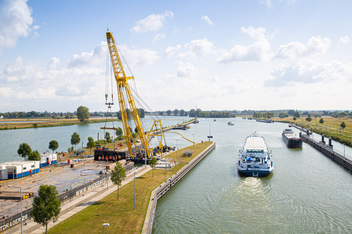 Met een grote kraan wordt een sluisdeur verwijderd bij de Maas in Lith